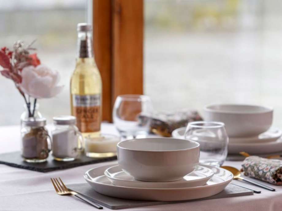 A dining room set up with napkins, plates, cutlery and flowers.