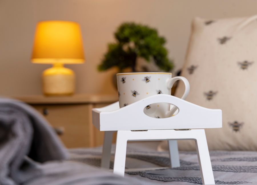 Breakfast tray with mug on bed, cosy scene with lamp and plants