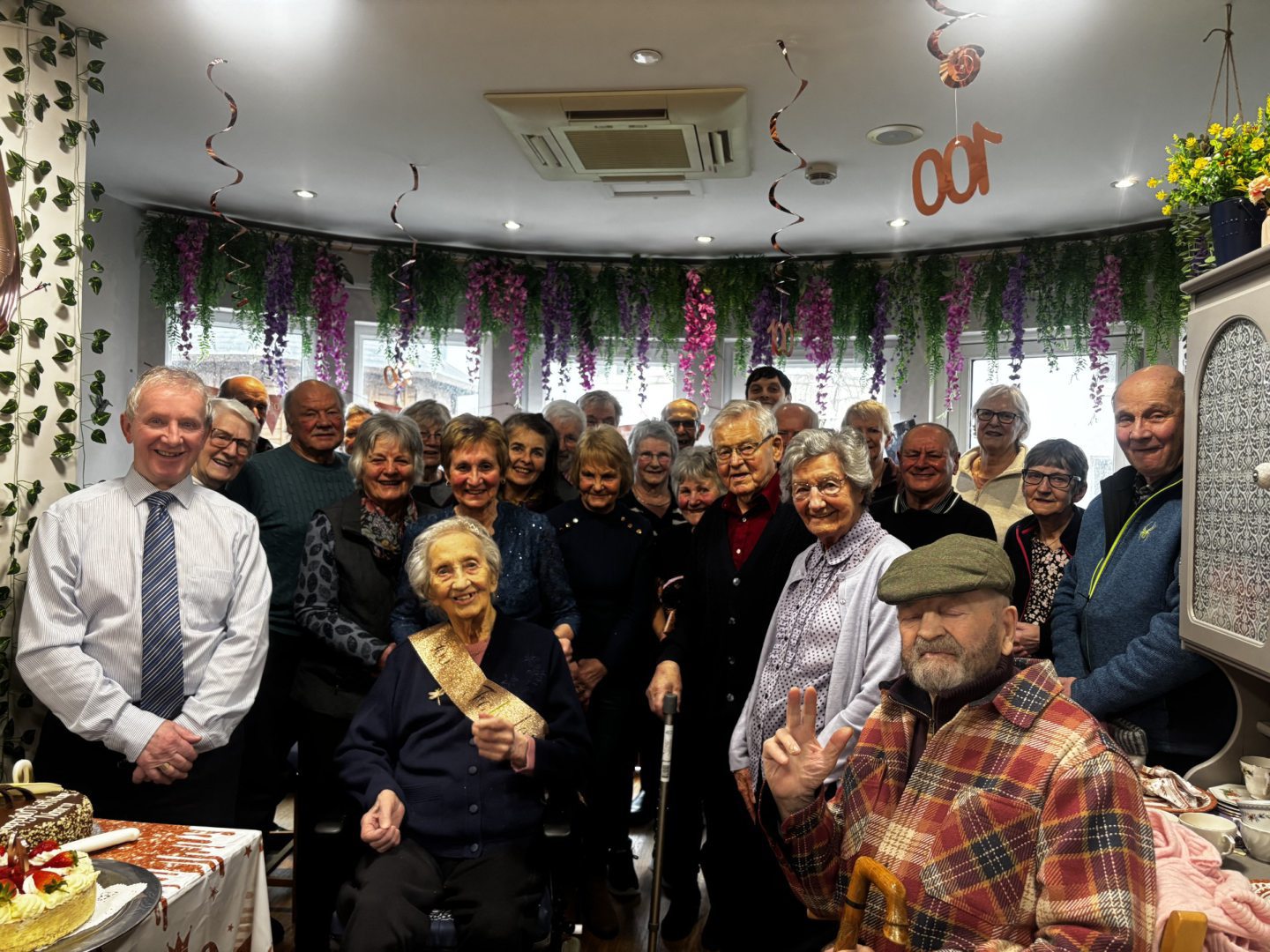 A large group of people gather around Nancy Lamb who celebrates her 100th birthday
