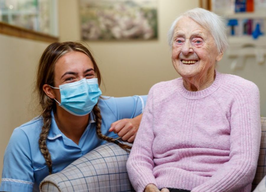 A staff member and resident are looking towards a camera and smiling