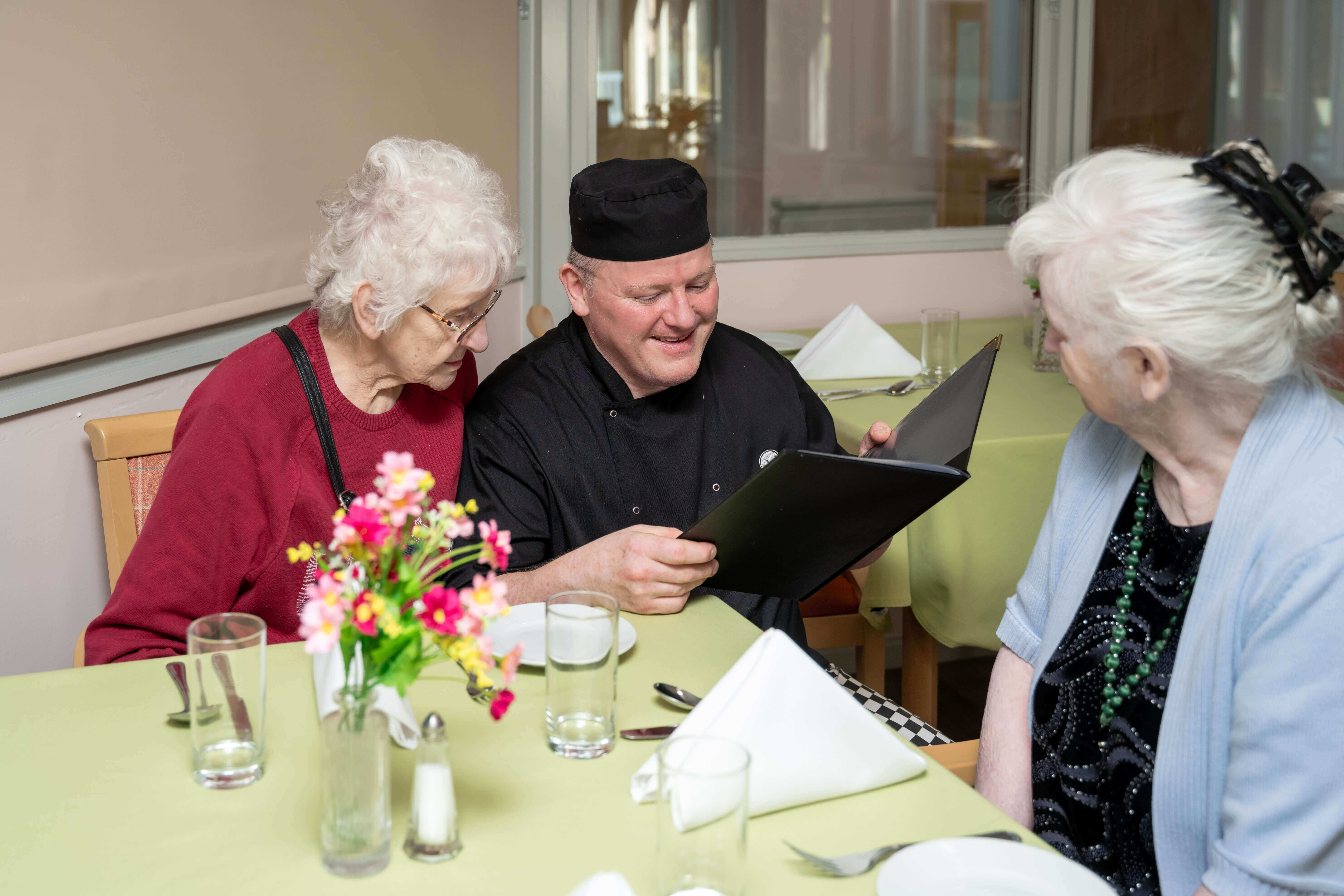 The care home chef and two residents are pictured in the dining room, working together to explore the menu options.