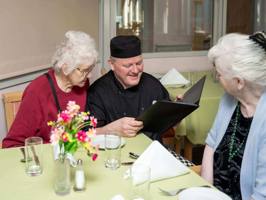The care home chef and two residents are pictured in the dining room, working together to explore the menu options.