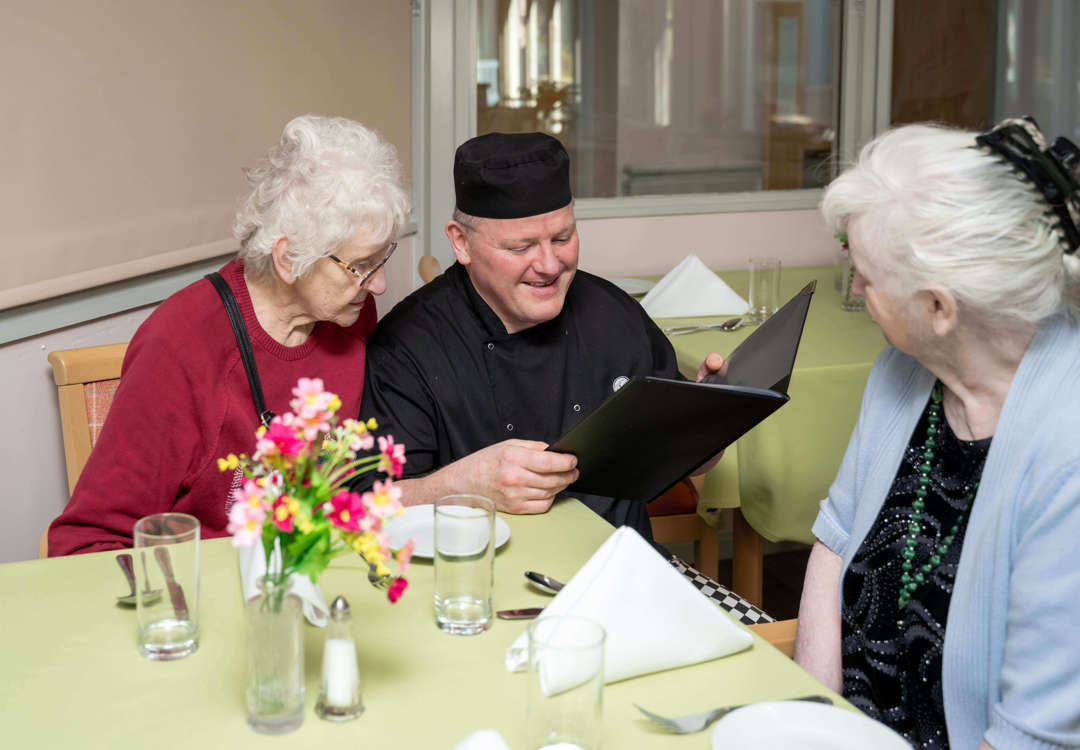 The care home chef and two residents are pictured in the dining room, working together to explore the menu options.