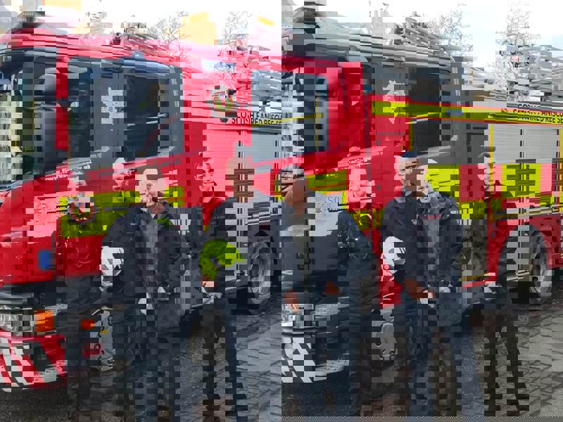 A care home resident stands surrounded by firefighters and a fire engine as he reminisces about his past career in the service