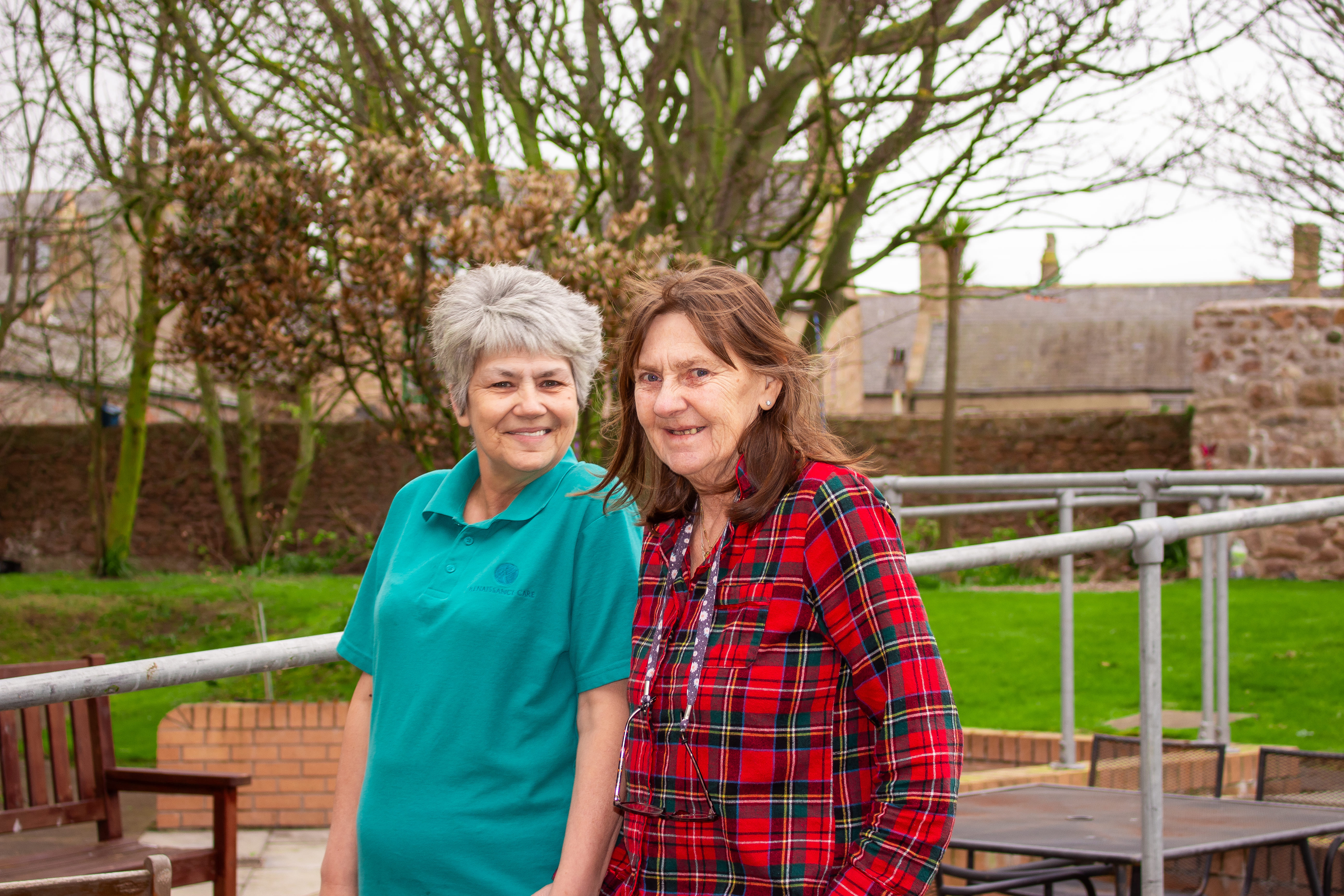 A care home resident and staff member enjoy a walk together in the care home garden.