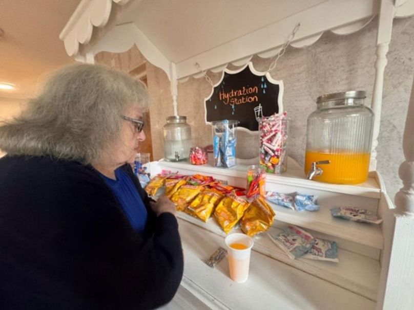 A woman independently gets juice and a treat from a snack trolley.