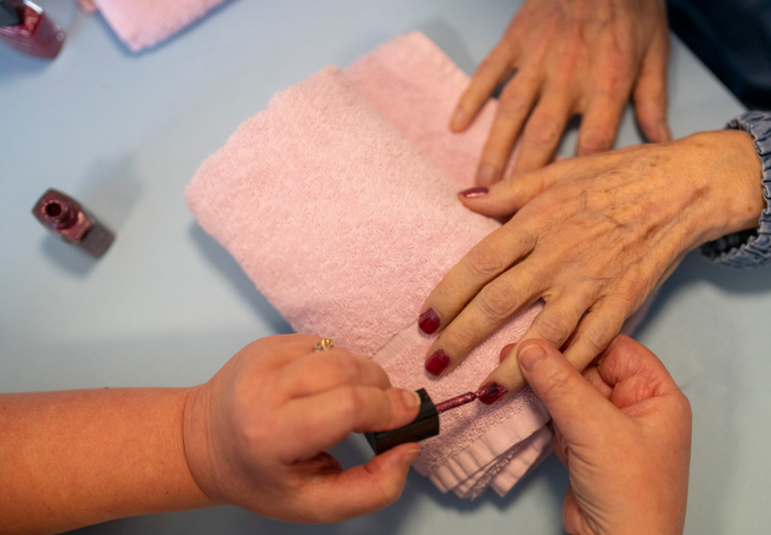 A staff member paints a care home residents nails