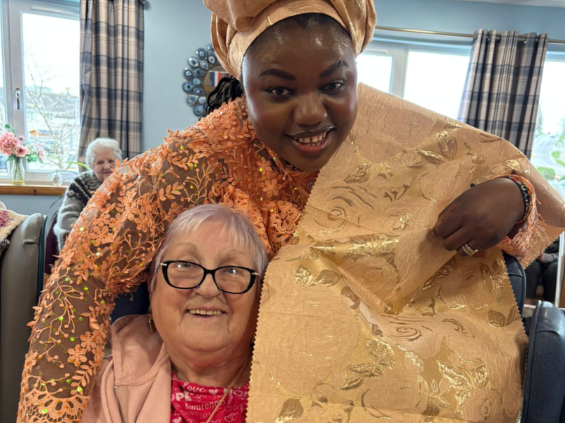 A staff member embraces a care home resident while in traditional dress as part of the homes cultural fashion show