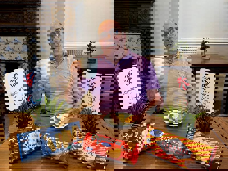 Care Home resident Ricky Tawse sits behind a table of biscuits holding up a cup of tea in search of britains most dunkable biscuit