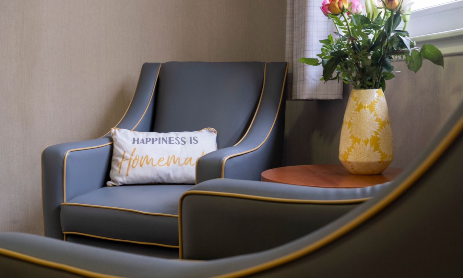 fresh flowers and two grey chairs next to a window within the home