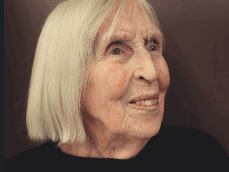 A profile portrait of an elderly woman with straight, chin-length white hair. She is looking off-camera with a gentle smile.