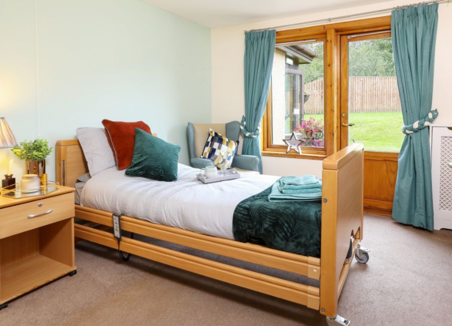A care home resident's bedroom with furniture and personal touches.