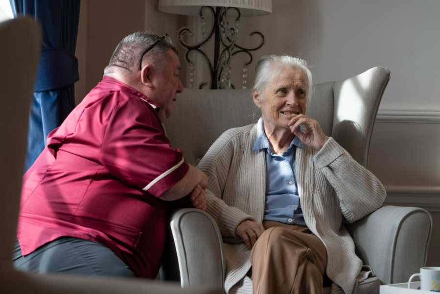 Staff member engages in conversation with a resident in a comfortable lounge setting