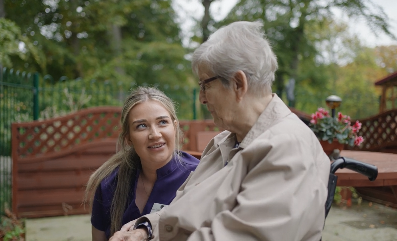 A staff member converses with a resident in the garden 