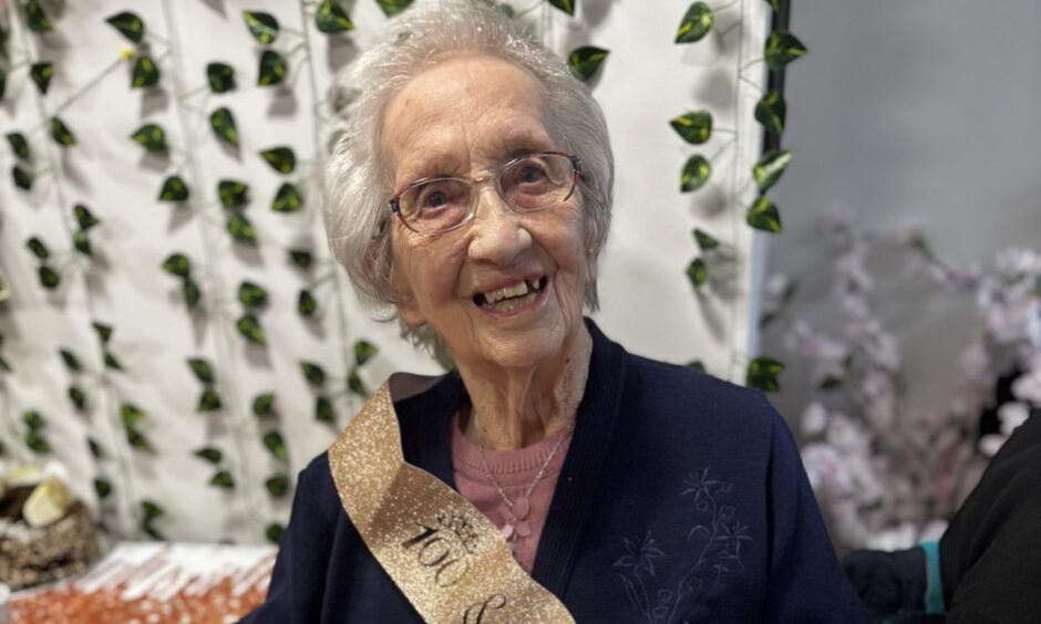 Nancy Lamb Celebrates her 100th Birthday. A head and shoulders shot of Nancy wearing a birthday sash and navy cardigan