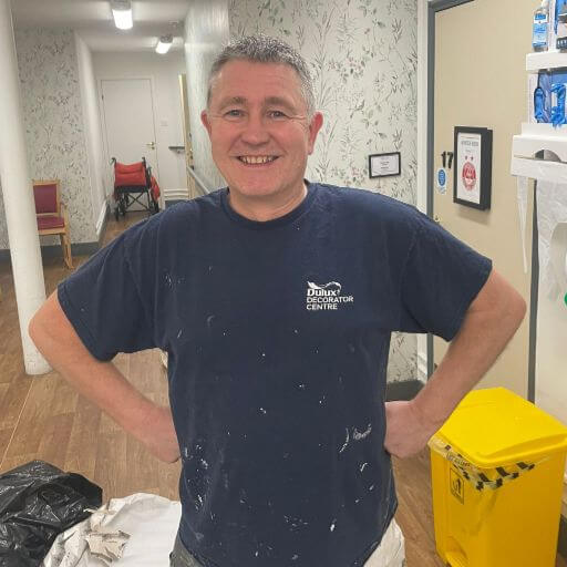 North team painter and decorator Simeon stands in his paint overalls in a care home hallway