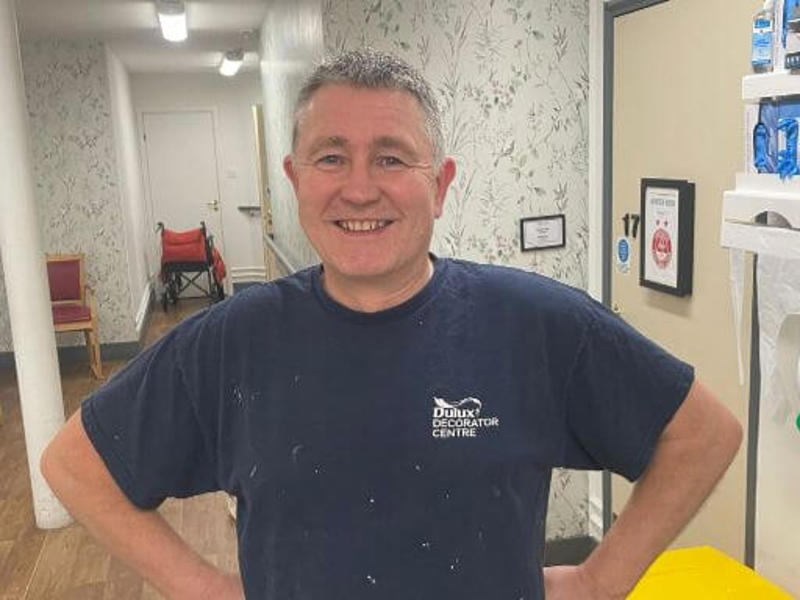 North team painter and decorator Simeon stands in his paint overalls in a care home hallway