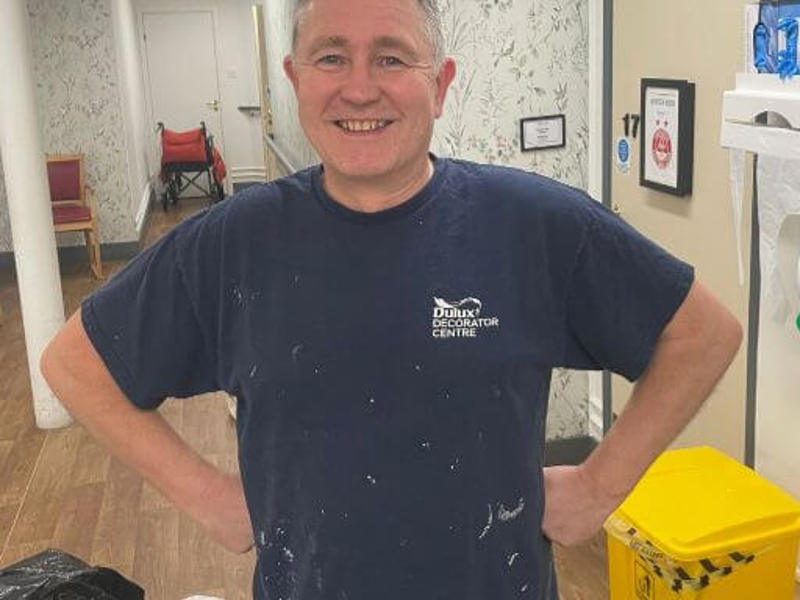 North team painter and decorator Simeon stands in his paint overalls in a care home hallway