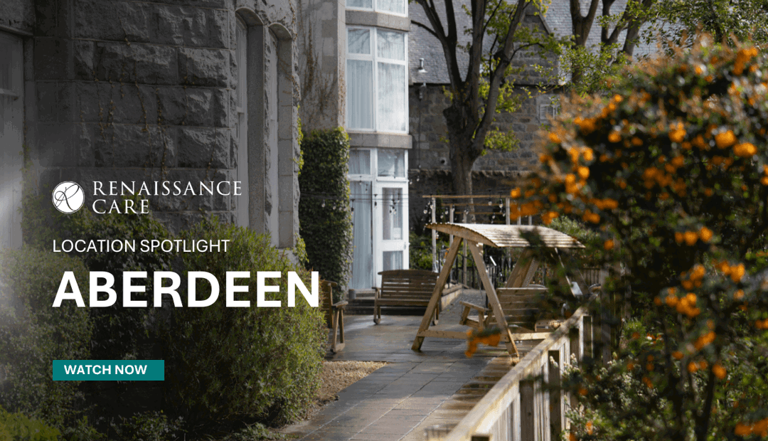 An autumnal garden with various bench seating and large grey granite building. A stone pathway and colourful shrubbery.  