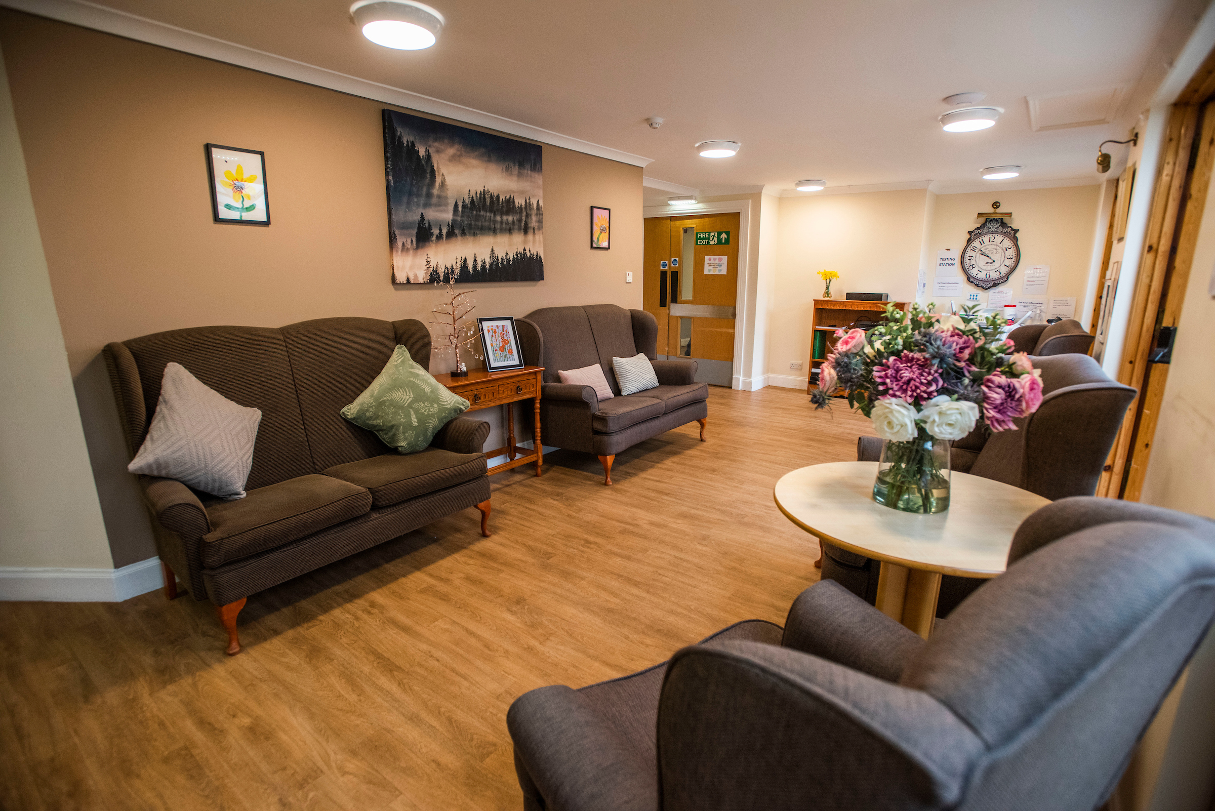 A communal space to sit and relax, there are an array of grey couches with various artworks and colourful decor 