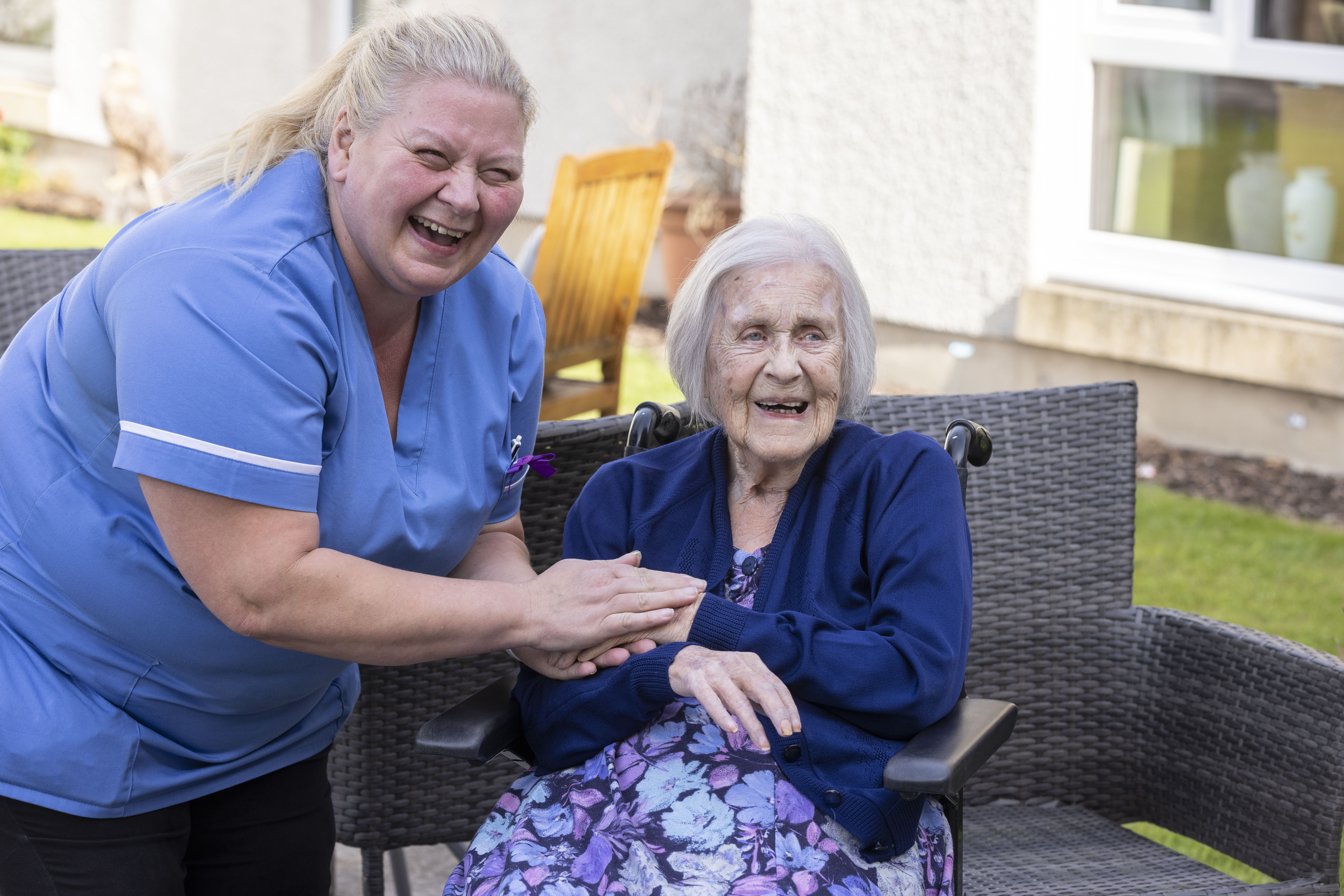 A staff member holds a care home residents hand in the garden 