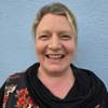 Headshot of care home manager, Terri Young. She has blonde hair which is tied up, and is wearing a black floral top