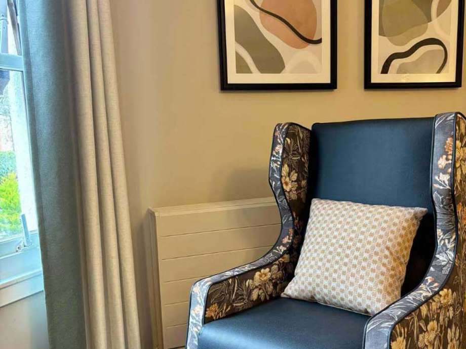 Floral navy chair positioned before a large window, with modern art on the wall