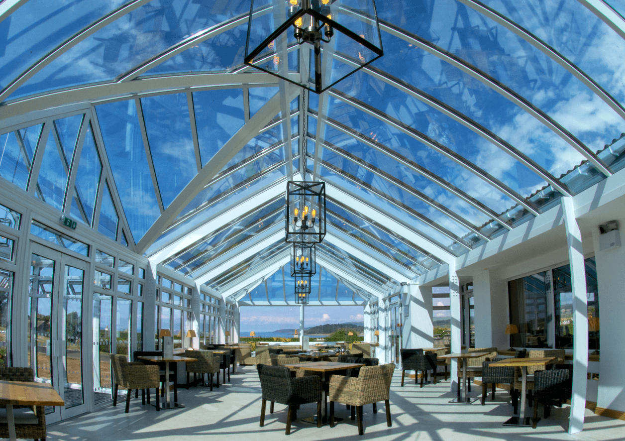 A bright, welcoming conservatory space with wicker seats and wooden tables throughout for dining