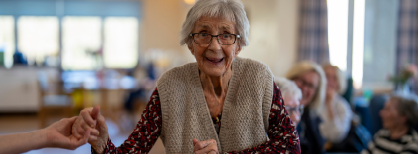 A woman smiles as she dances in a communal lounge