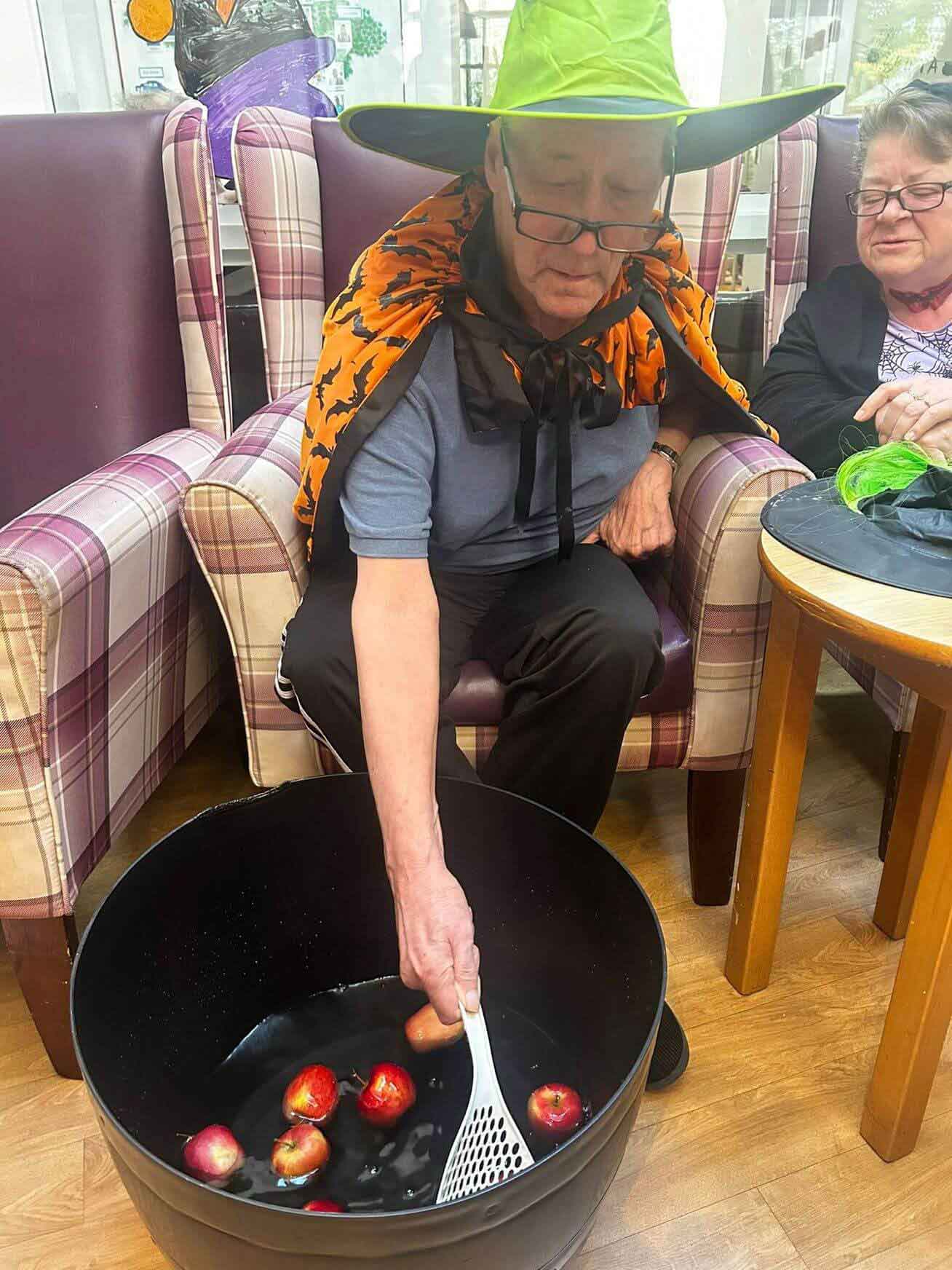 A care home resident engages in an adapted version of dooking for apples this halloween 