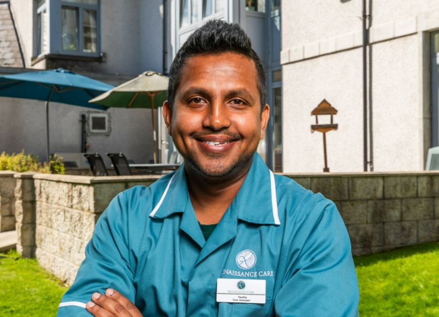 A staff member smiles outside the care home