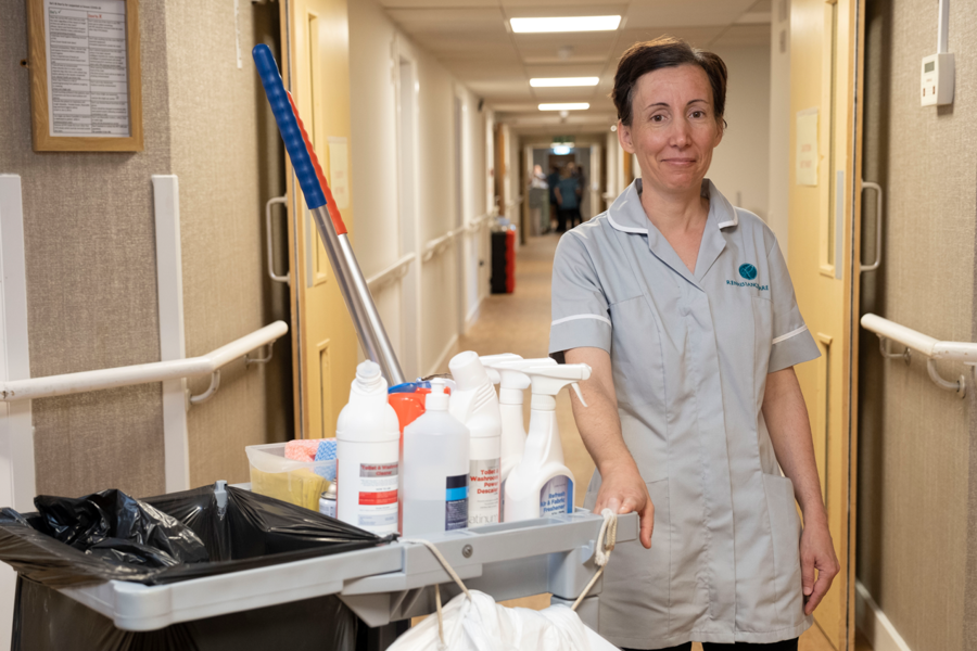 A member of the domestic staff team stands by a cleaning cart