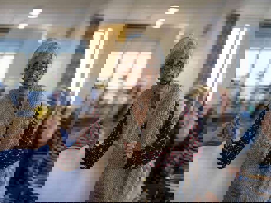 Woman enjoys dancing, holding hands with a care assistant (out of view).