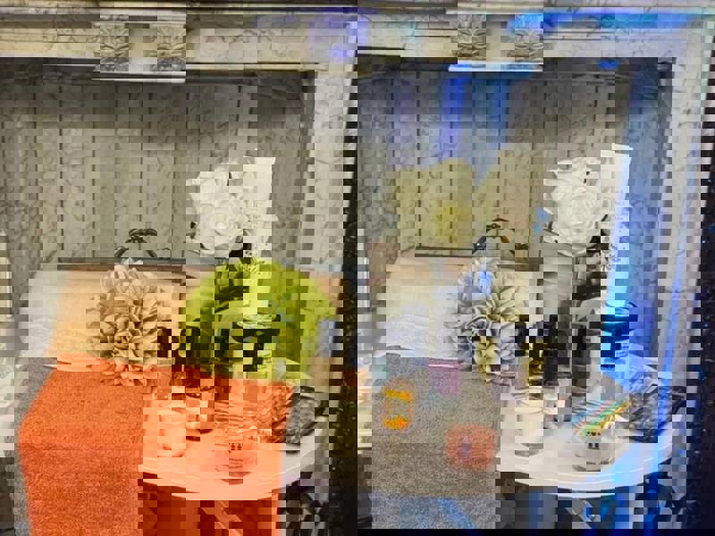 A selection of nail polishes and skin care sits on a white table alongside two orange coloured towels - ready for a namaste care session.