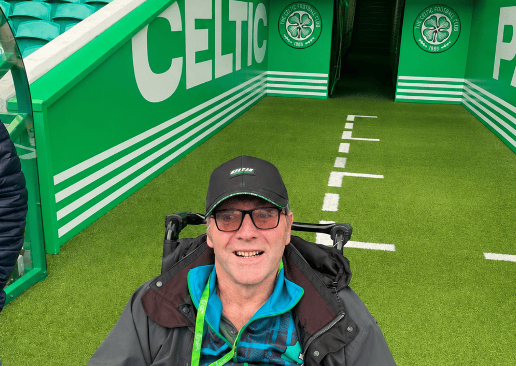 Care home resident David poses on the lawn at Celtic Park in front of the player's tunnel 