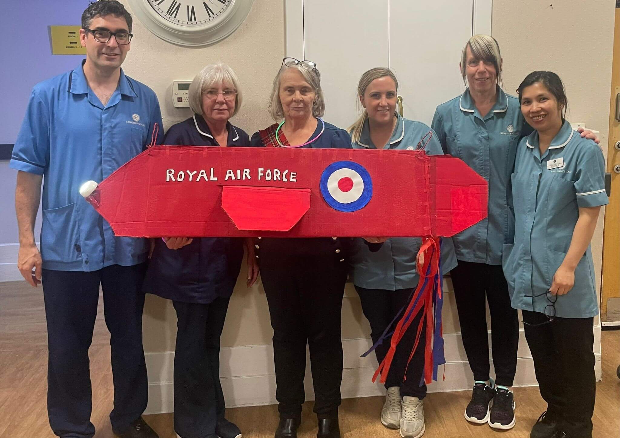six of our staff members stand behind a cardboard 'red arrows' display as part of their Scottish Week Celebrations