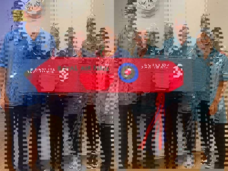 six of our staff members stand behind a cardboard 'red arrows' display as part of their Scottish Week Celebrations