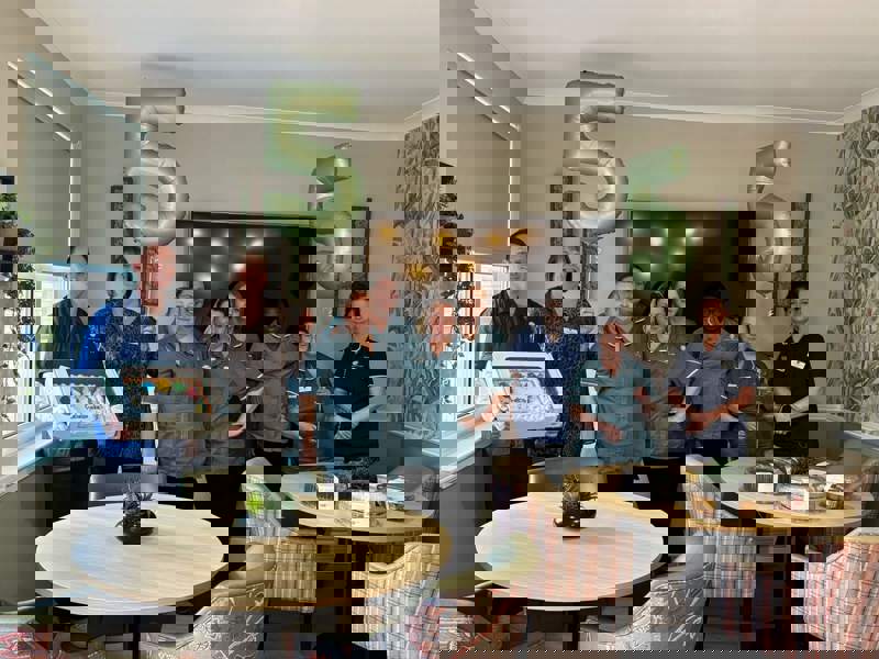 Members of the staff team stand proudly, with two '5' balloons and an assortment of cakes to celebrate the success of a recent inspection